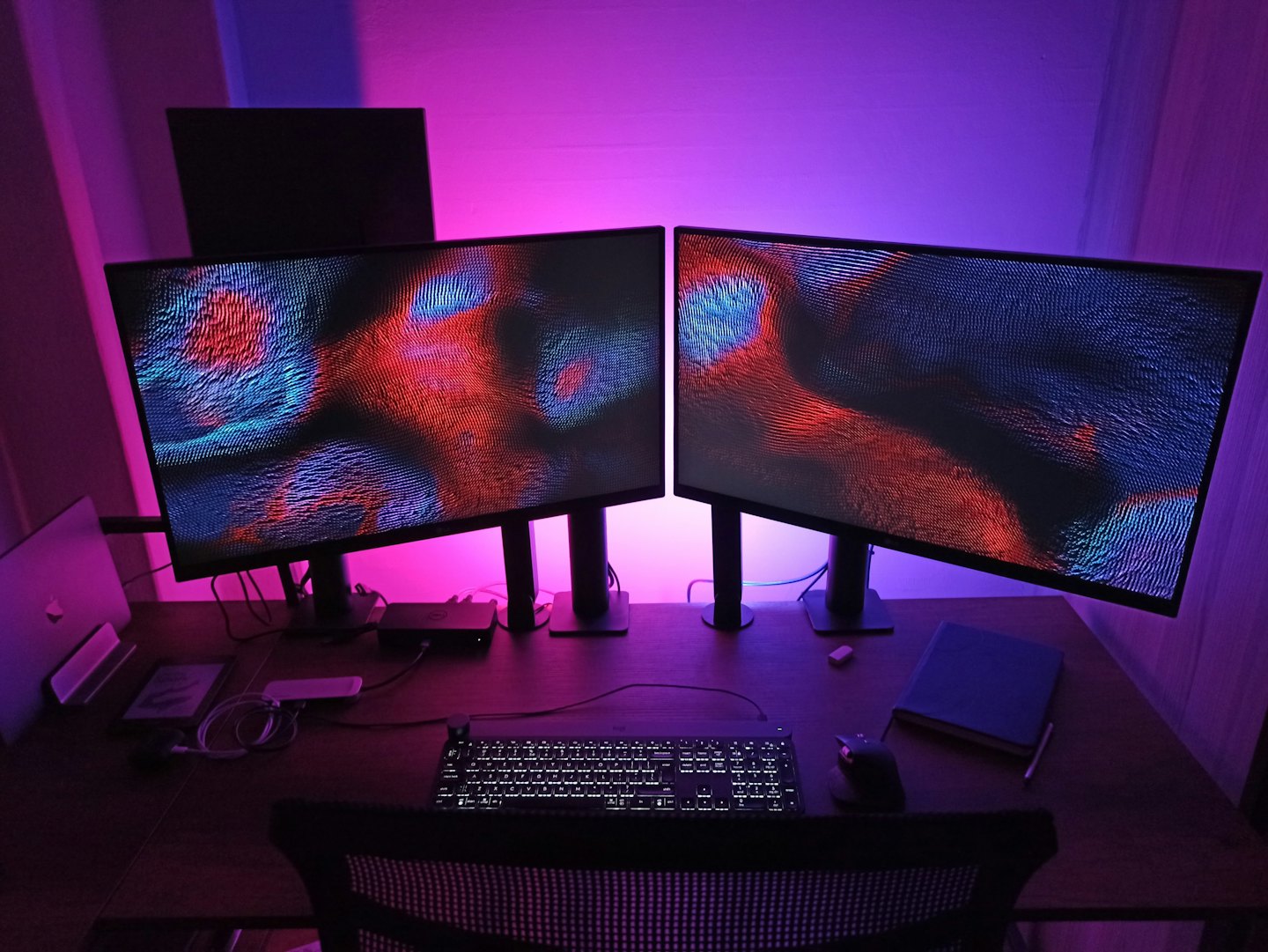 Computerarbeitsplatz mit zwei Monitoren, die abstrakte Kunst zeigen.