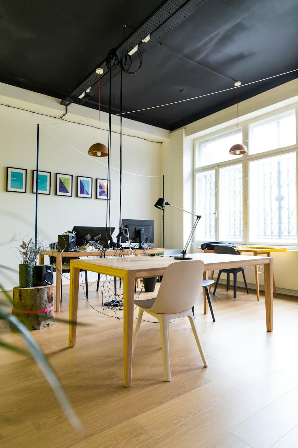 Modernes Büro mit hellen Holzschreibtischen und großen Fenstern.