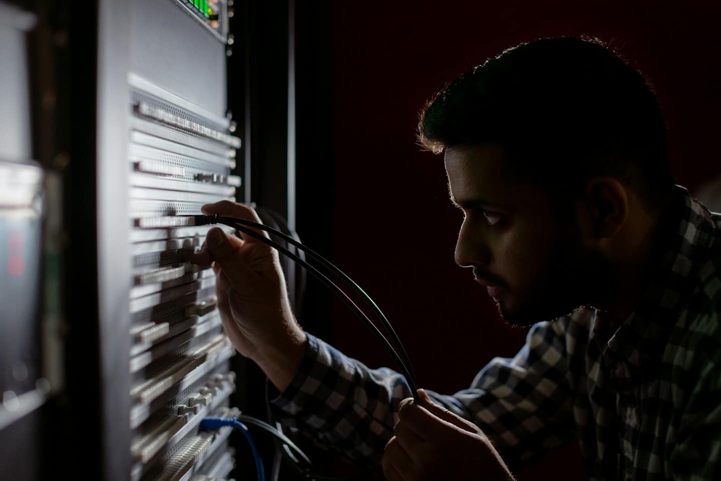 Mann schließt Kabel an einem Server-Rack in einem Rechenzentrum an.