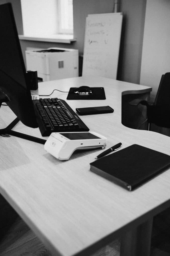 Office desk with computer, payment terminal, and printer.