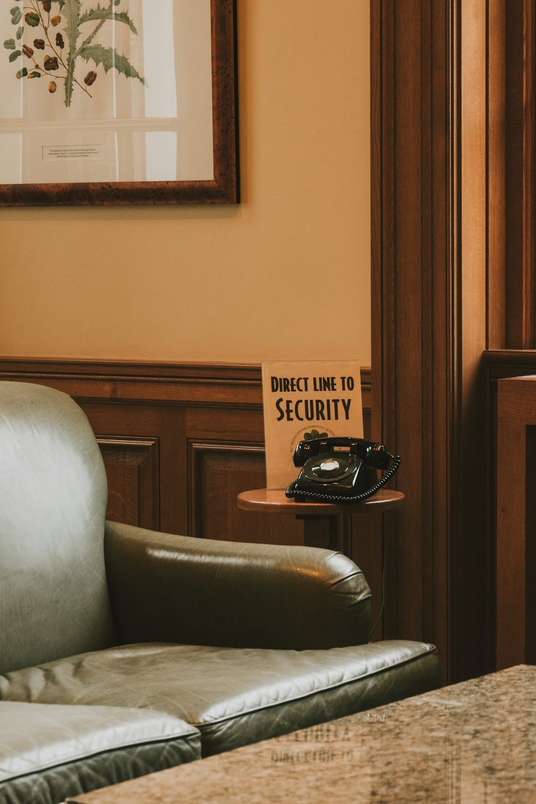 Vintage black rotary phone on a wooden table with security sign.