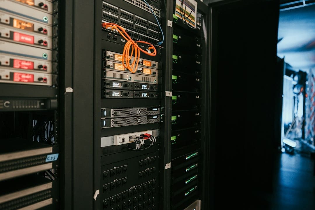 Server racks filled with glowing equipment and orange network cables.